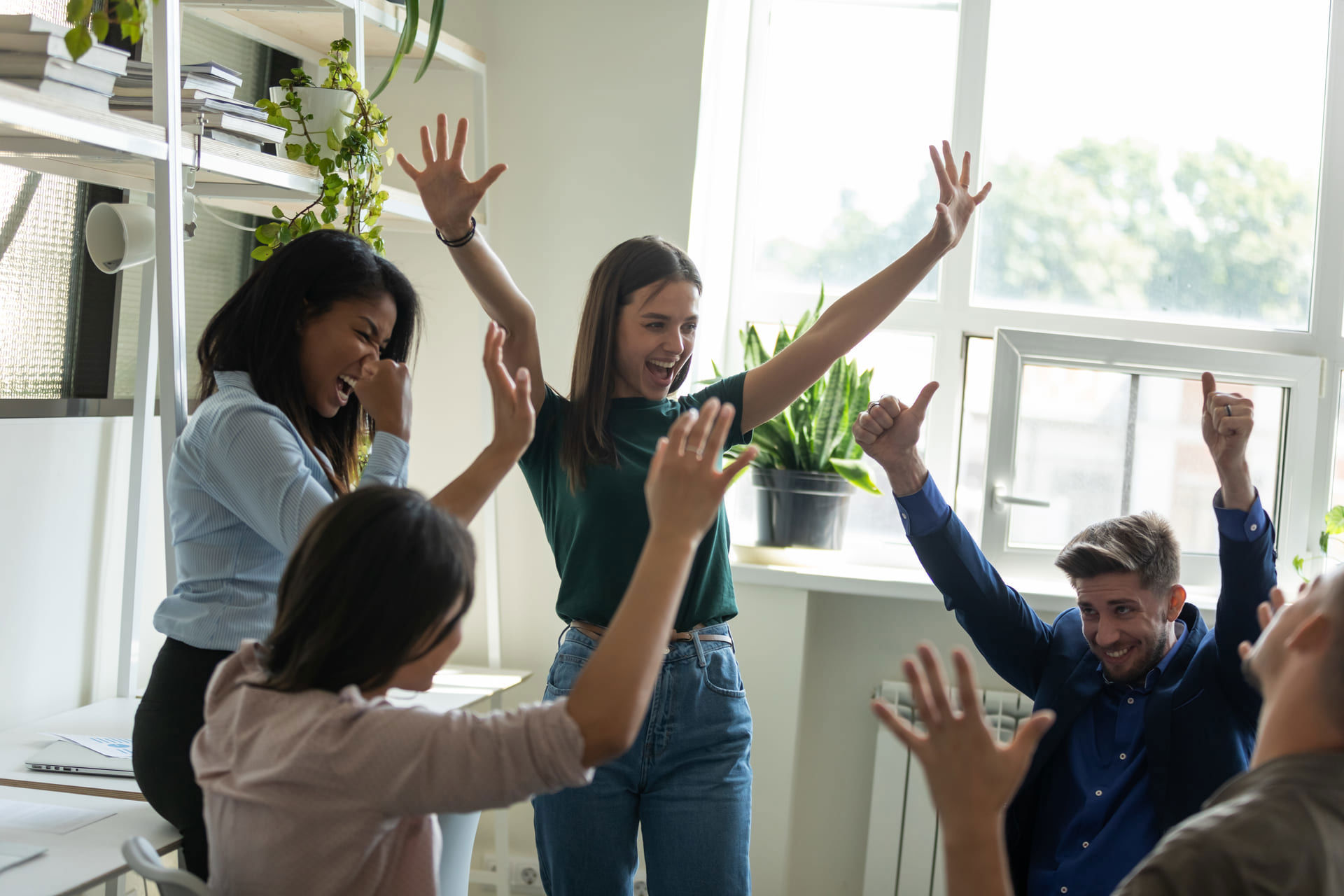 Diverse team celebrating a collective achievement in the workplace.