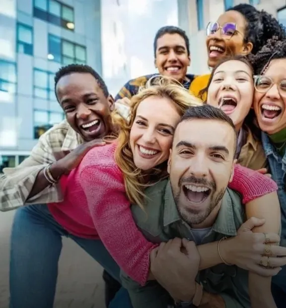 Group of smiling friends taking a picture outside of a modern office building