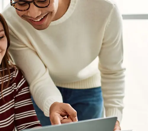 A girl and a boy looking over a laptop