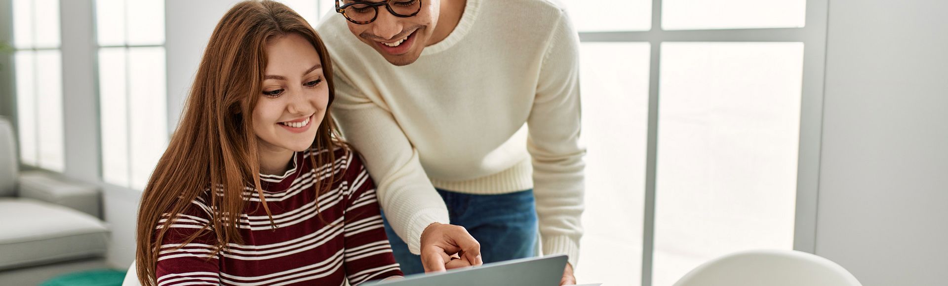 A girl and a boy looking over a laptop