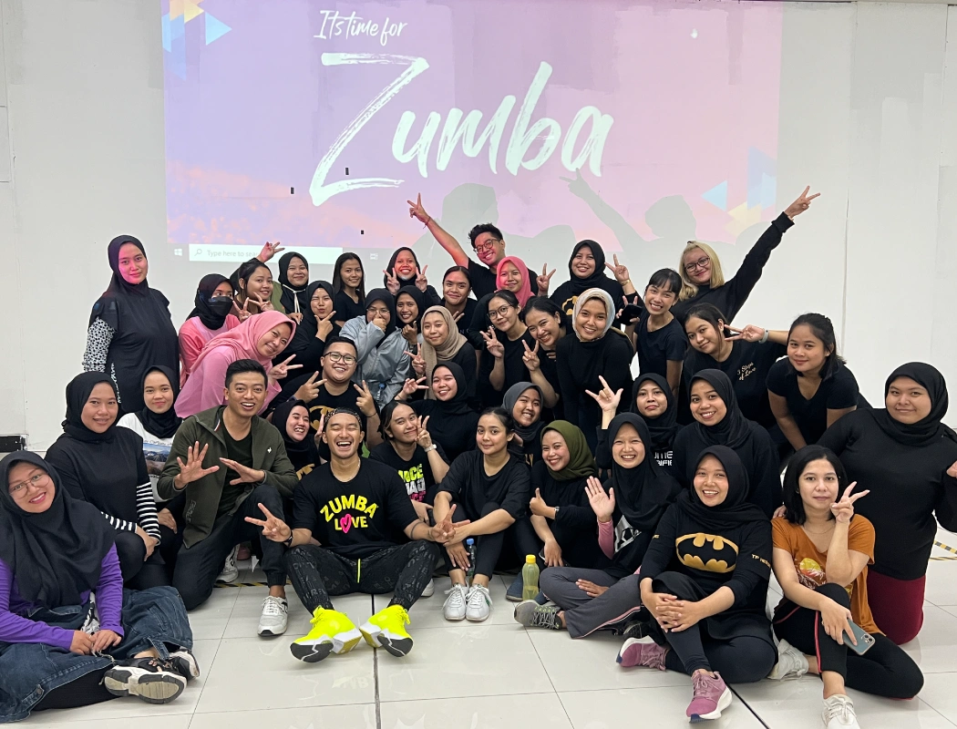 A diverse group of participants joyfully poses after a Zumba class together.