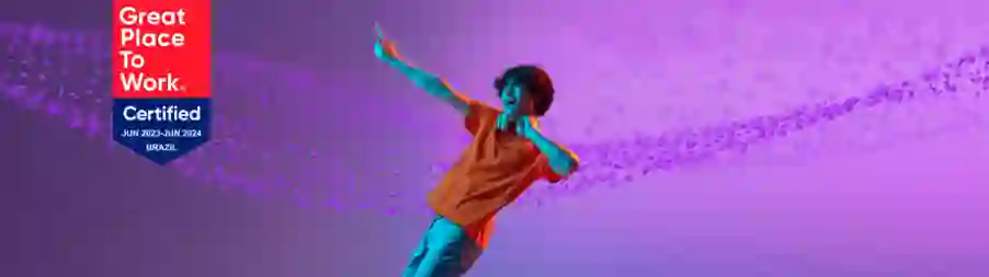 Smiling young man dancing with Great Place to Work Brazil 2023–2024 certification badge on purple background