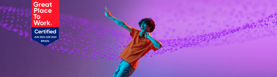 Smiling young man dancing with Great Place to Work Brazil 2023–2024 certification badge on purple background