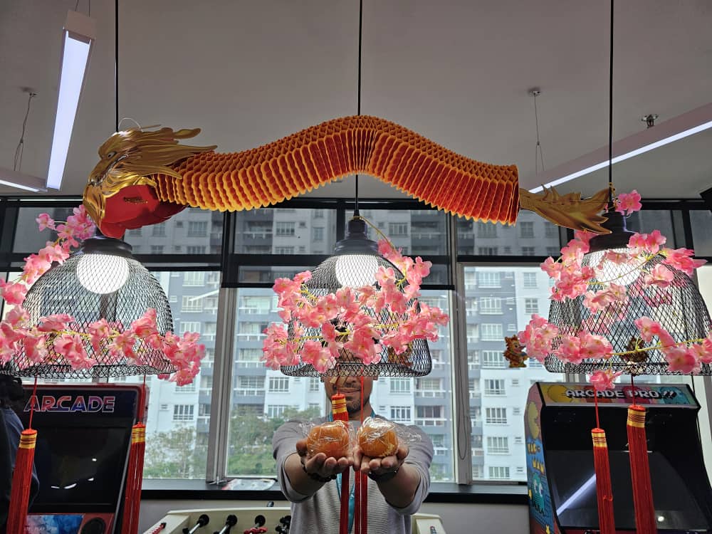 Person holding traditional Chinese pastries under decorative dragon and cherry blossoms in arcade