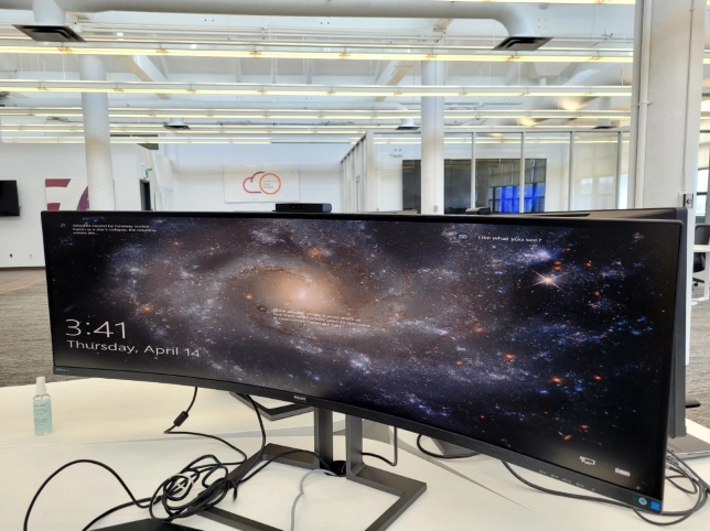 Ultra-wide curved monitor displaying galaxy image on office desk