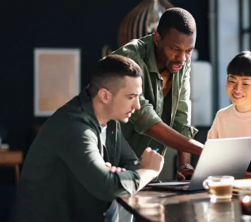 TP team members collaborating around a laptop to improve customer experience.