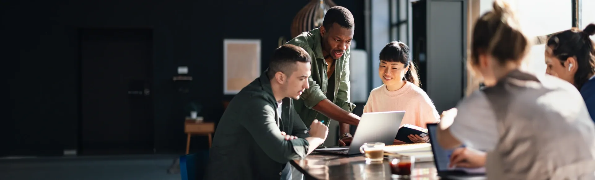 TP team members collaborating around a laptop to improve customer experience.