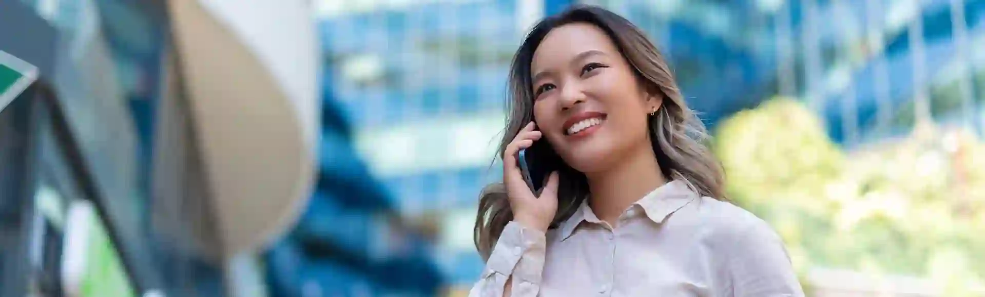 Smiling Asian business woman talking on the phone in the streets
