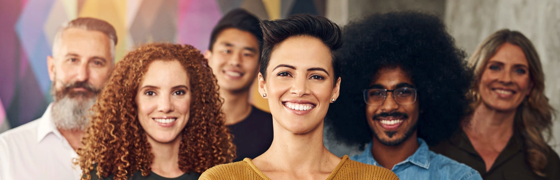 A diverse group of three men and three women smiling together, conveying equality, unity, and a harmonious workplace environment.