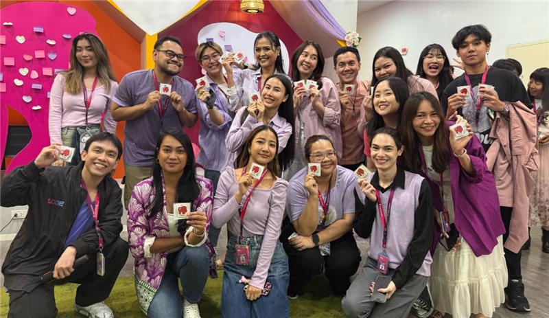 TP employees wearing purple holding small cards during office event