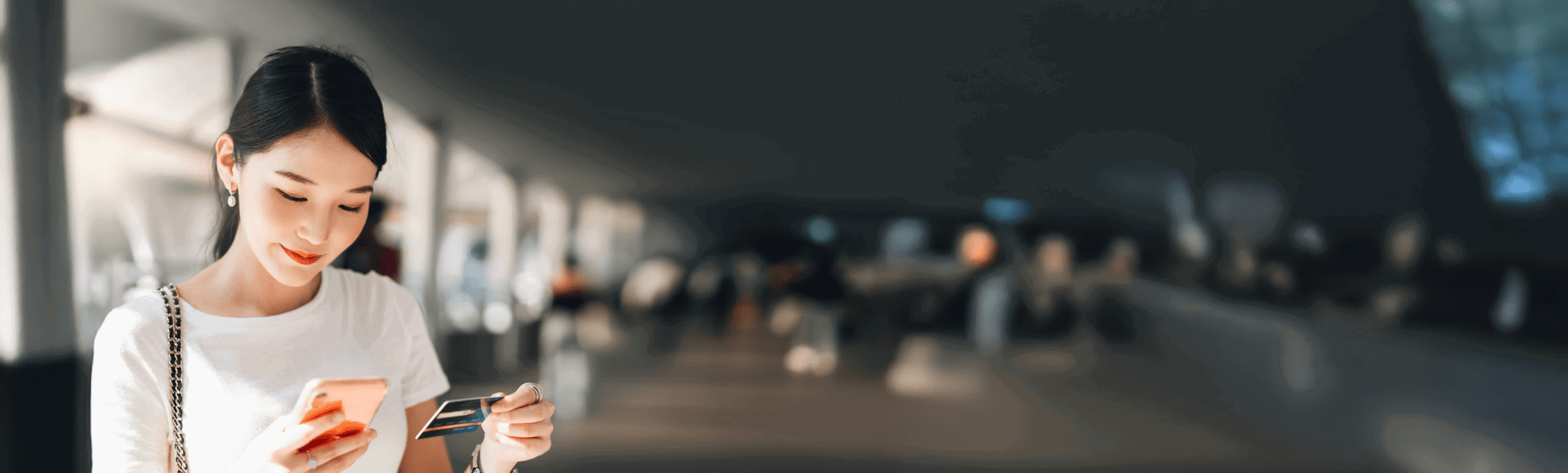 Asian lady looking at the cellphone while holding card Asian lady looking at the cellphone while holding card