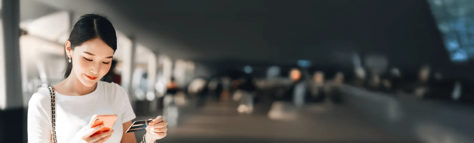 Asian lady looking at the cellphone while holding card