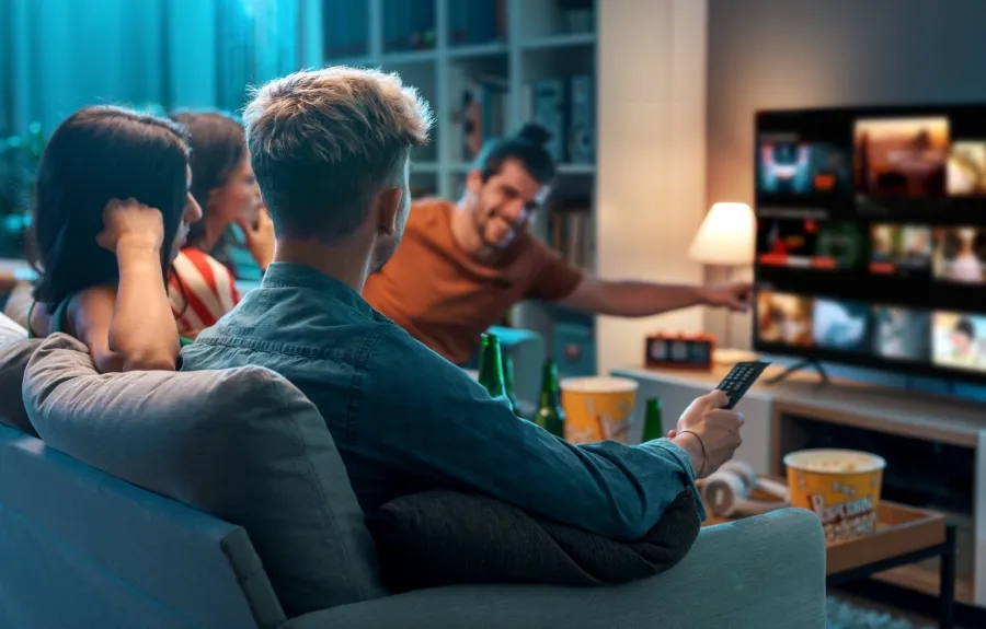 Group of friends watching streaming content together on a television at home.