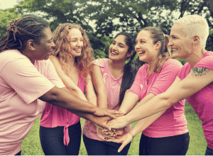 Fünf Personen in rosa Hemden legen ihre Hände gemeinsam in die Mitte.