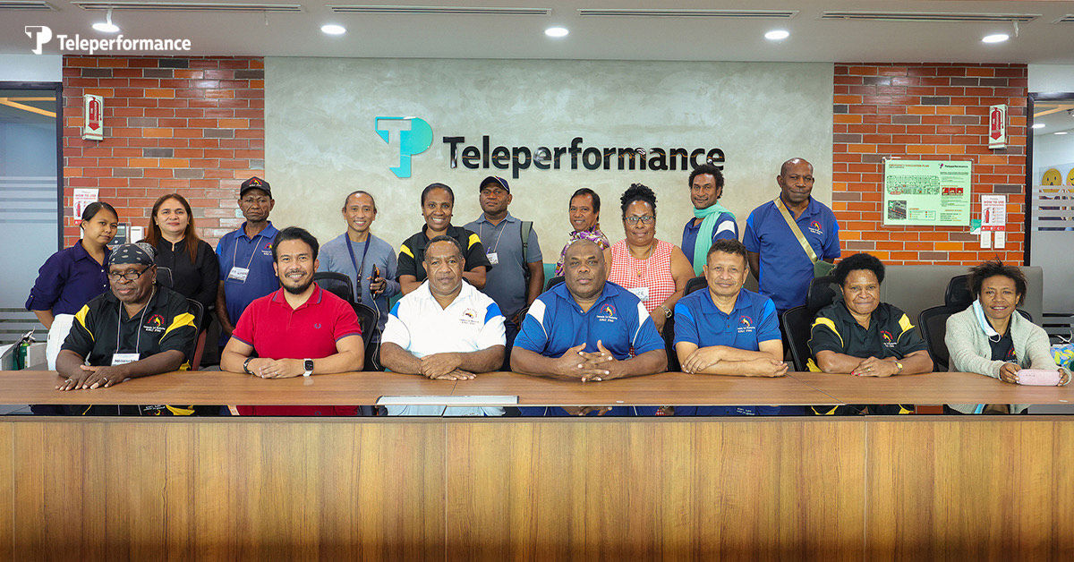 TP employees posing for a group photo inside a company office with the TP logo on the wall.