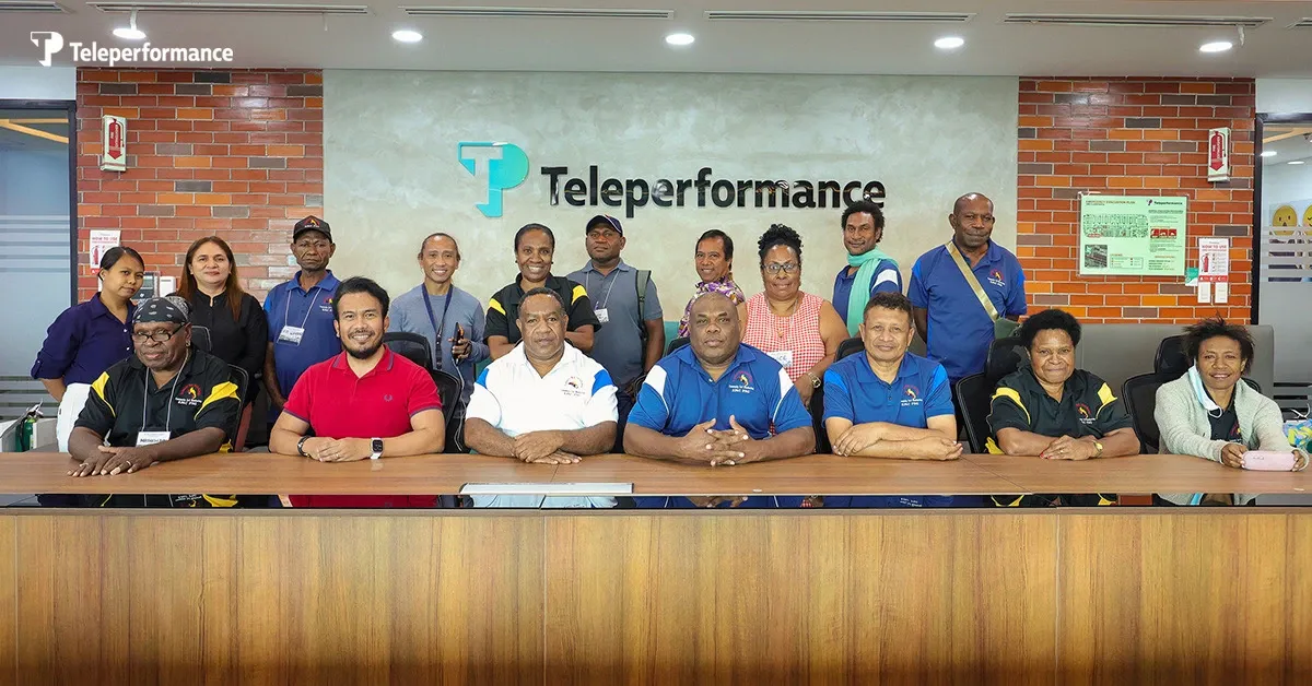 TP employees posing for a group photo inside a company office with the TP logo on the wall.