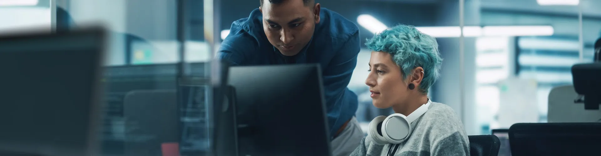 Two IT professionals collaborating while reviewing code on a computer screen.