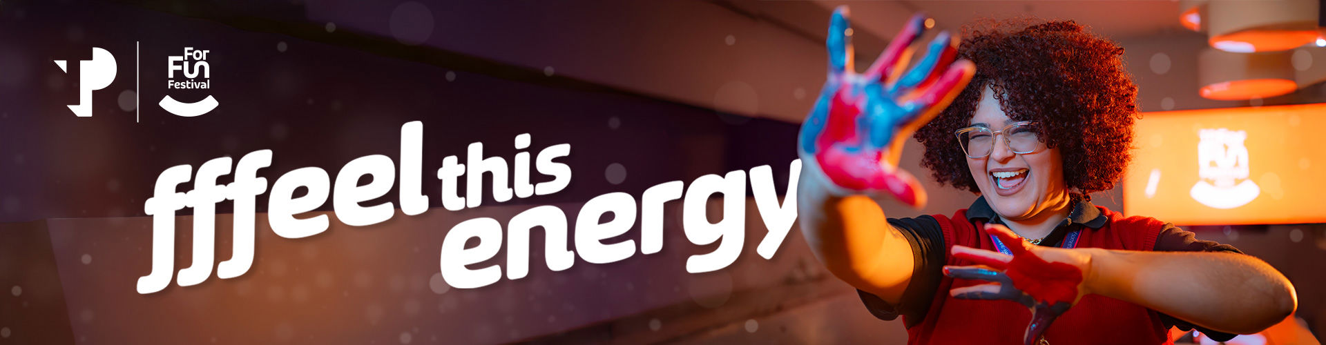 TP For Fun Festival banner with the phrase “Ffeel this energy” and a smiling person with painted hands.