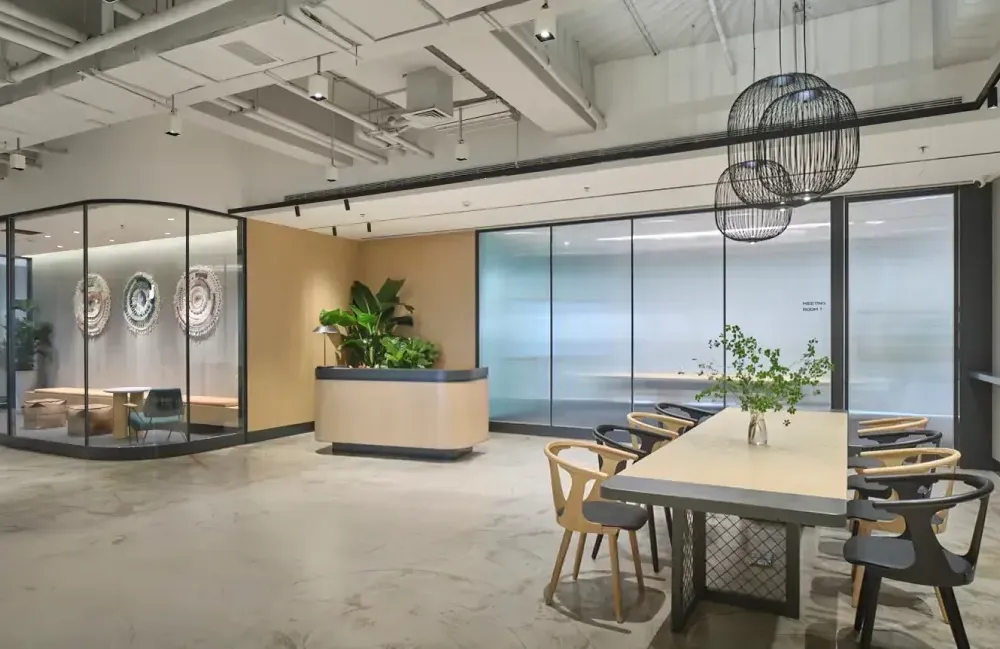 A modern, bright open-plan office space with glass meeting rooms, stylish lighting, and a collaborative lounge area.