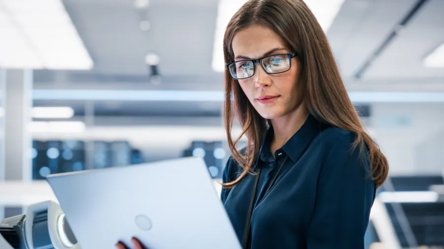 Professional woman using a laptop in a modern office environment.