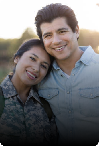 Smiling couple taking a photo together; the woman is dressed in military uniform and the man is in casual clothing.