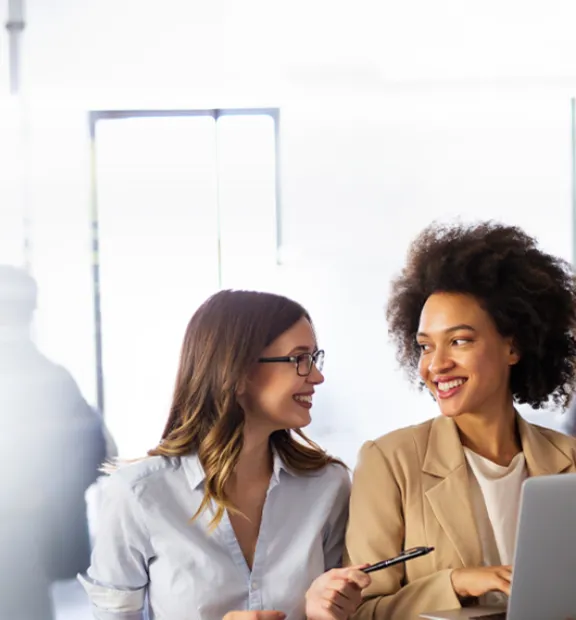 Two colleagues smiling while working together in an office.