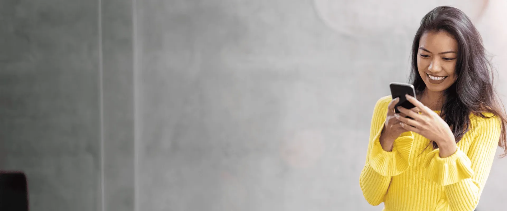 Smiling young Asian girl browsing her smartphone