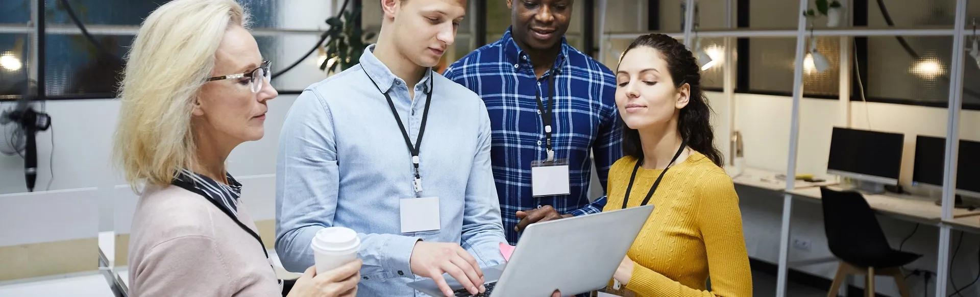 Diverse team reviewing information together on a laptop in a modern office.