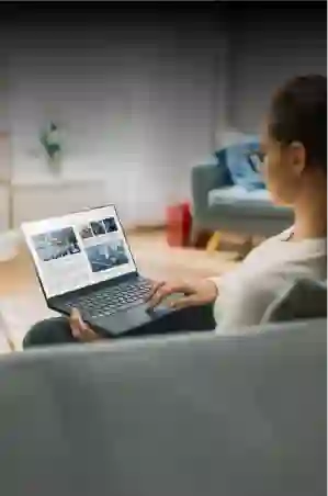 Woman working on her laptop while sitting on a sofa at home