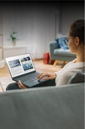Woman working on her laptop while sitting on a sofa at home