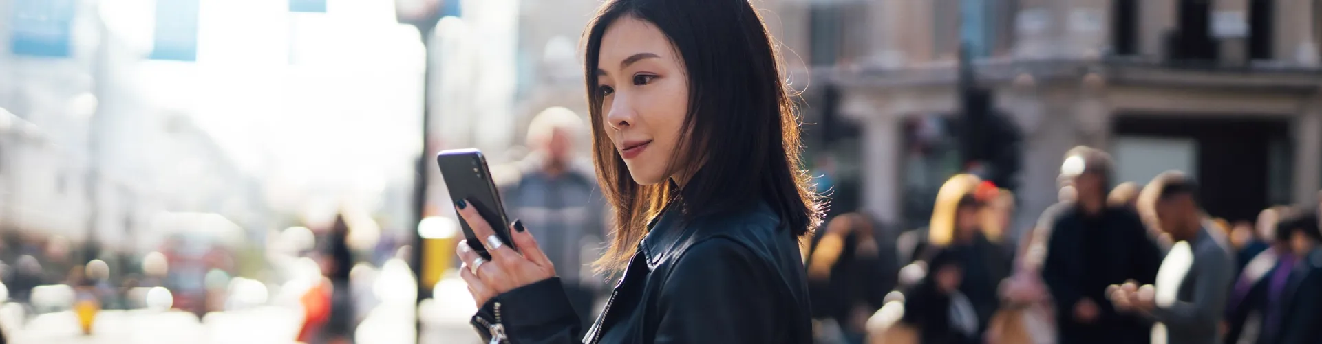 Professional woman using smartphone in a busy city street.