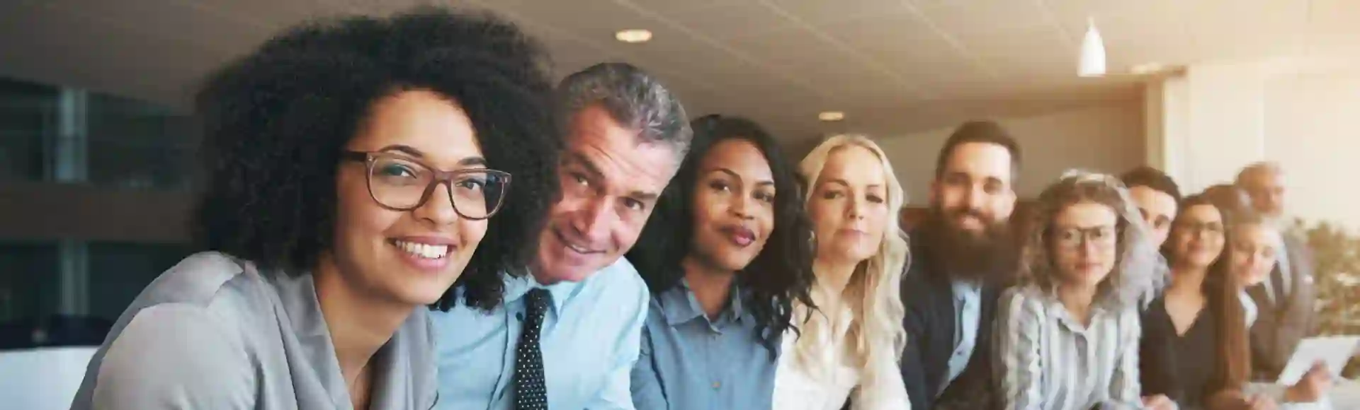 Group of smiling employees in an office, representing TP’s support in managing insurance licensing risks.