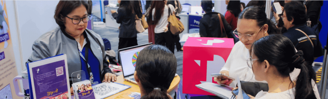 TP female employee at a TP booth interacting with female students