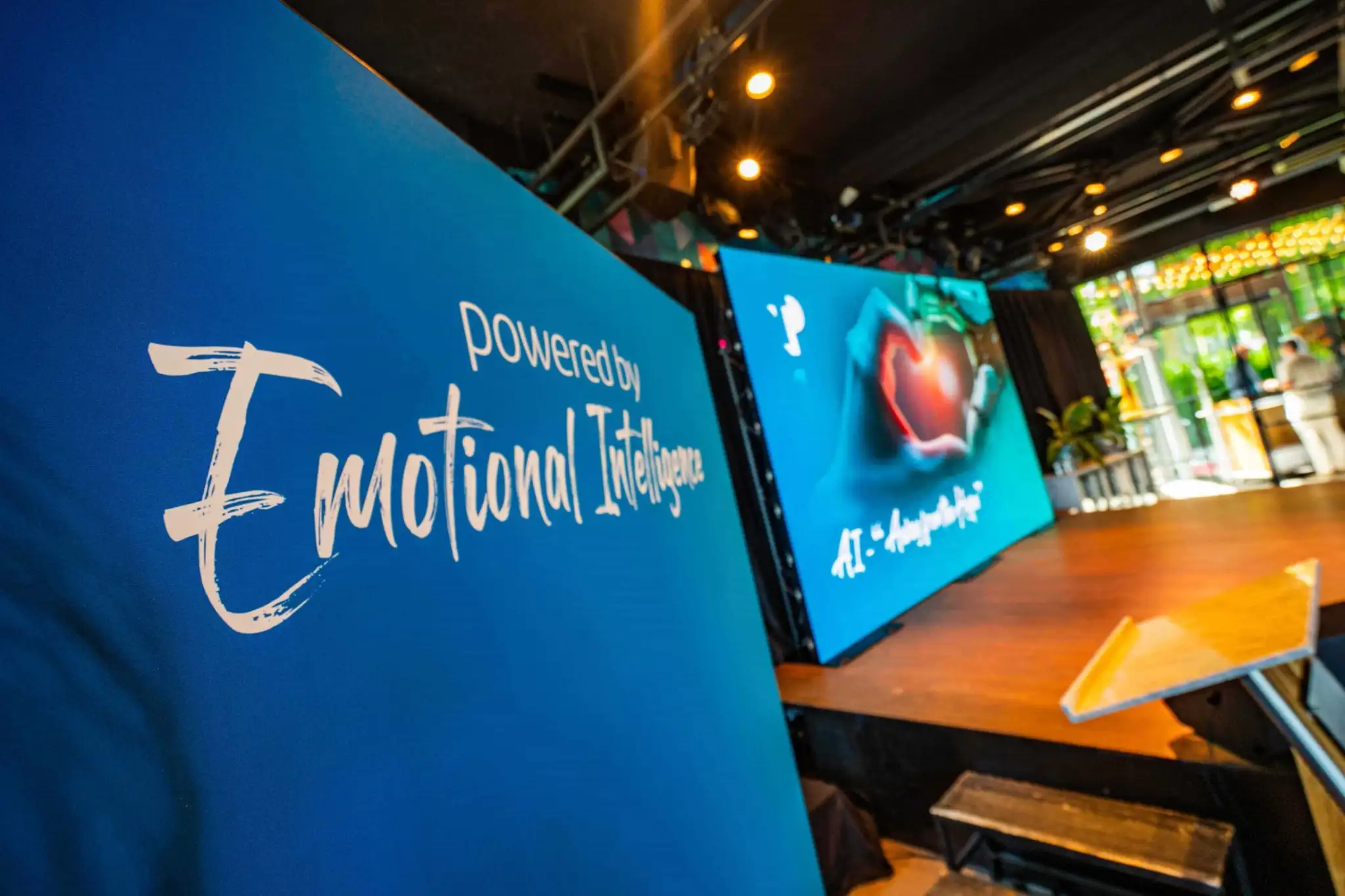 Event stage with large blue banners reading Powered by Emotional Intelligence