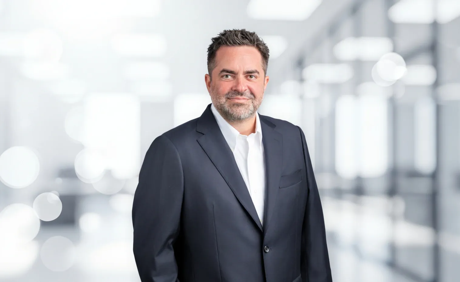 A professional headshot of a confident businessman in a dark suit.