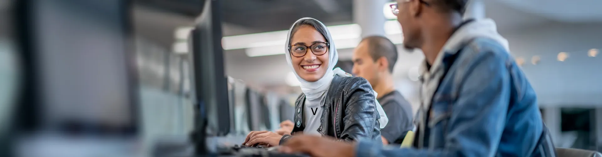 Customer support agents collaborating at computers in a modern contact center.