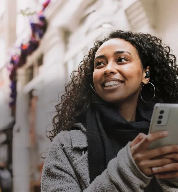 Women smiling with a smartphone on her hand.
