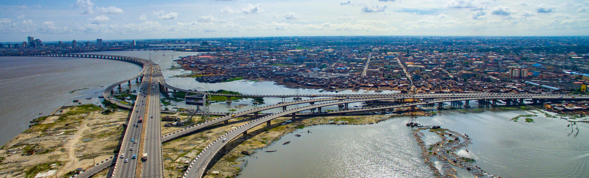 A city landscape of a highway leading into a major city, with rivers/water either side of the highway