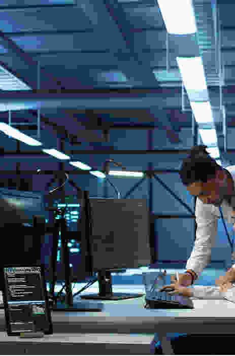 Two professionals collaborating in a modern office, one pointing at a laptop.