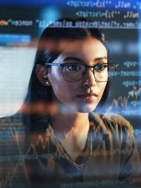 Woman coding on a computer with 3D prompts displayed on the screen.