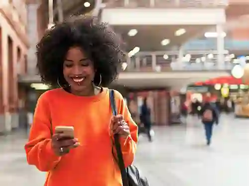 Young African smiling woman browsing her cellphone