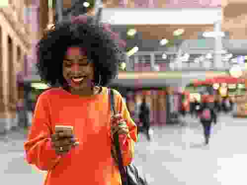 Young African smiling woman browsing her cellphone