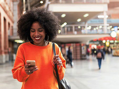 Young African smiling woman browsing her cellphone