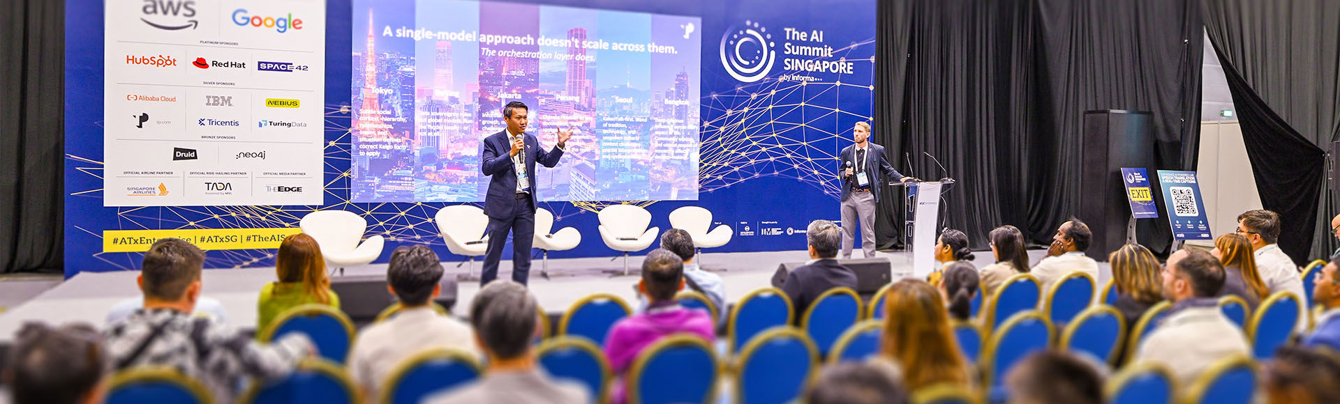 A speaker delivers a keynote at The AI Summit Singapore to a large audience.