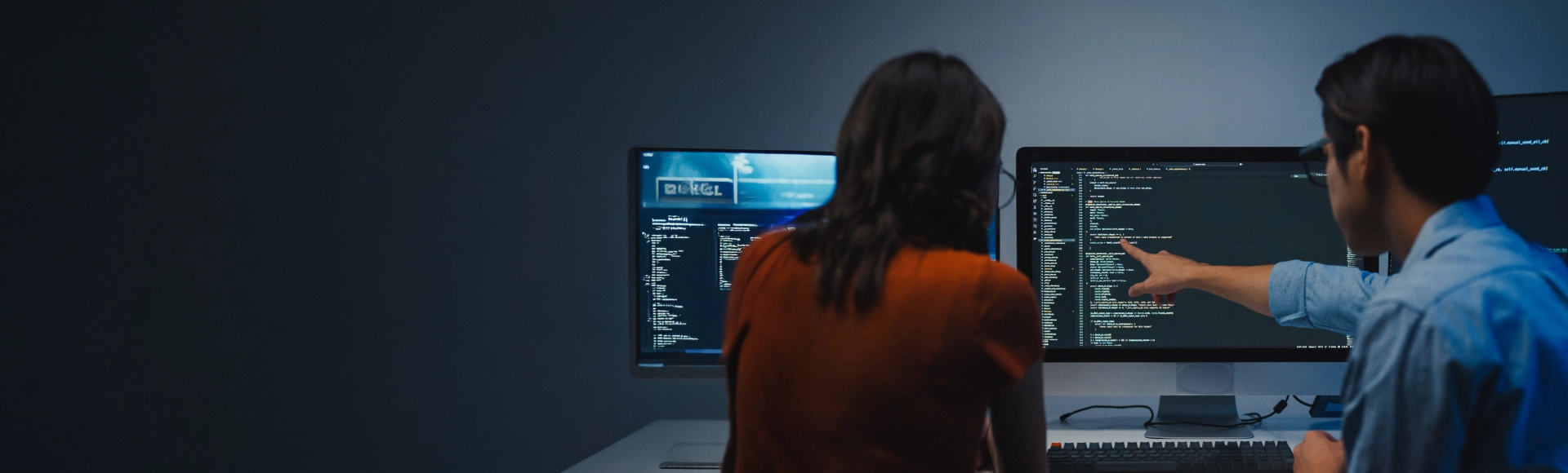 Professionals analyzing code across multiple monitors in a collaborative workspace.