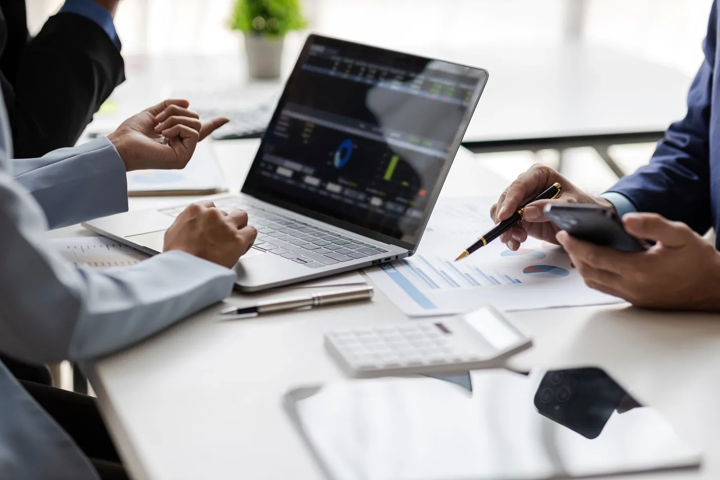 Business professionals reviewing charts and performance data together on a laptop during a meeting.