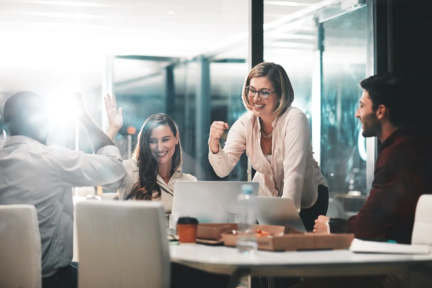 Team members celebrating together around a laptop during a collaborative meeting.