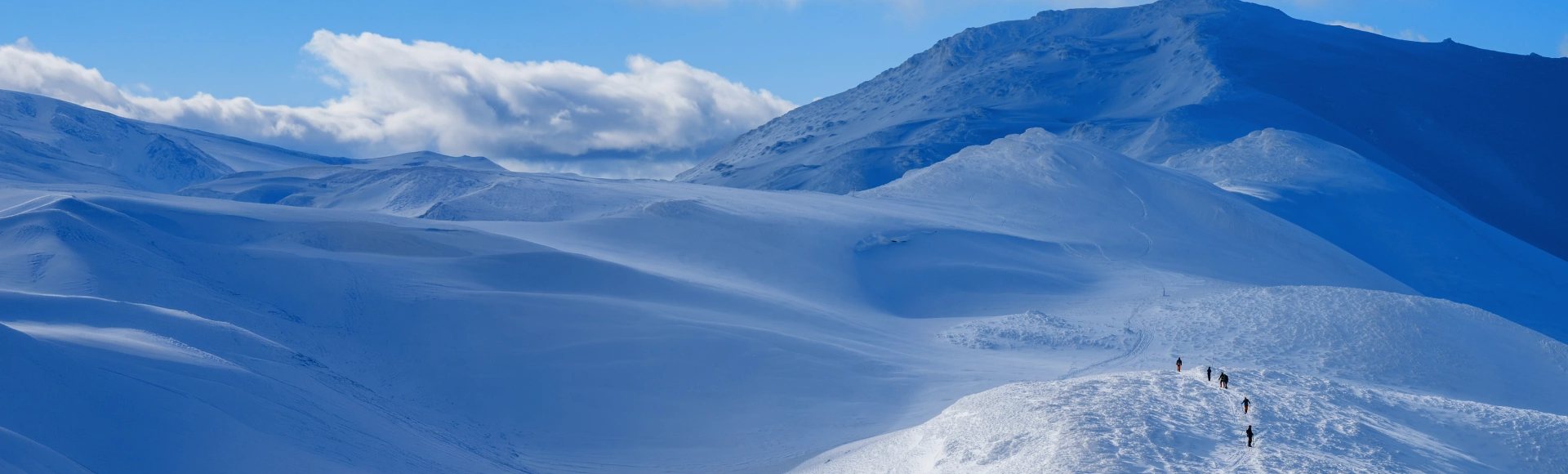 Group of explorers hiking along the summit of a frozen mountain.