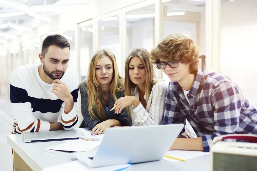 Young team collaborating around a laptop during a meeting in a modern office.