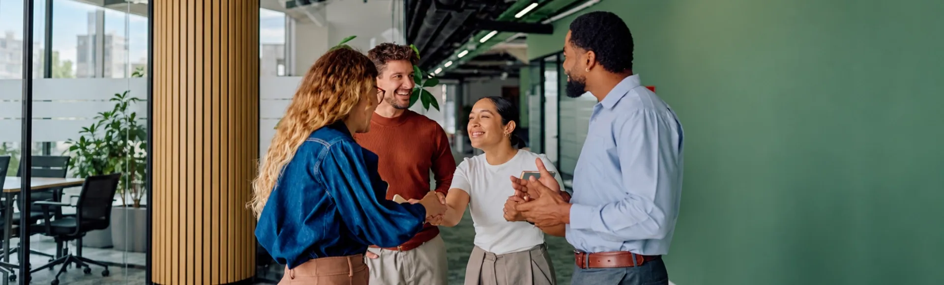 Colleagues greeting each other in a vibrant office with green walls.